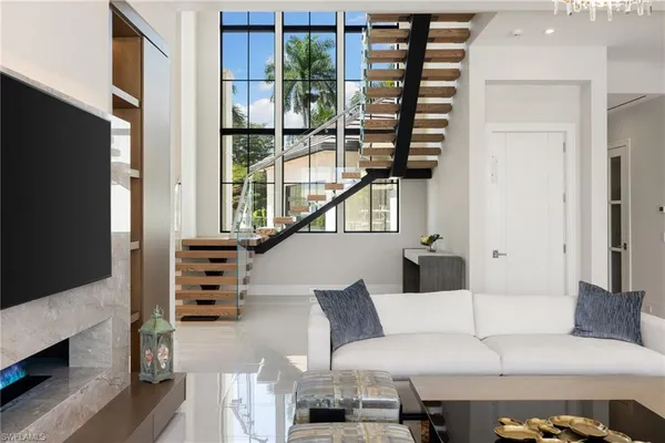 a living room with furniture a flat screen tv and floor to ceiling window