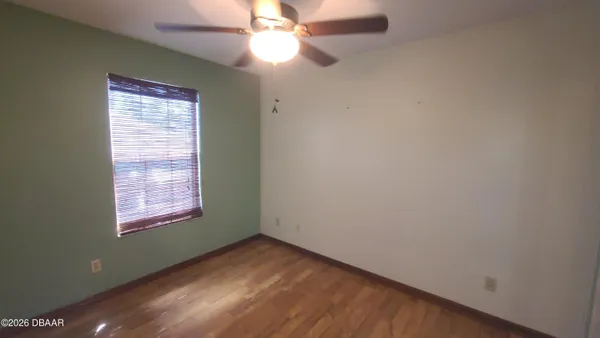 an empty room with wooden floor fan and windows
