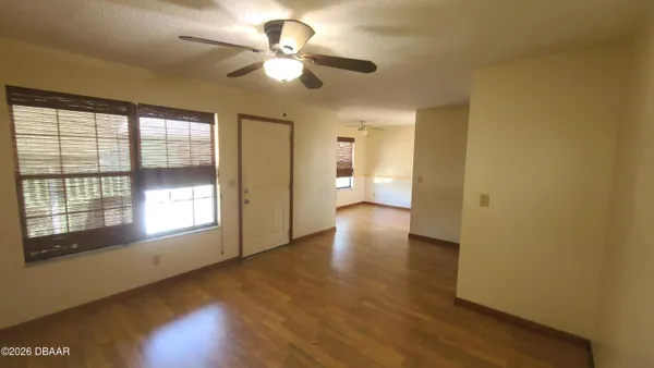 a view of an empty room with a window and wooden floor
