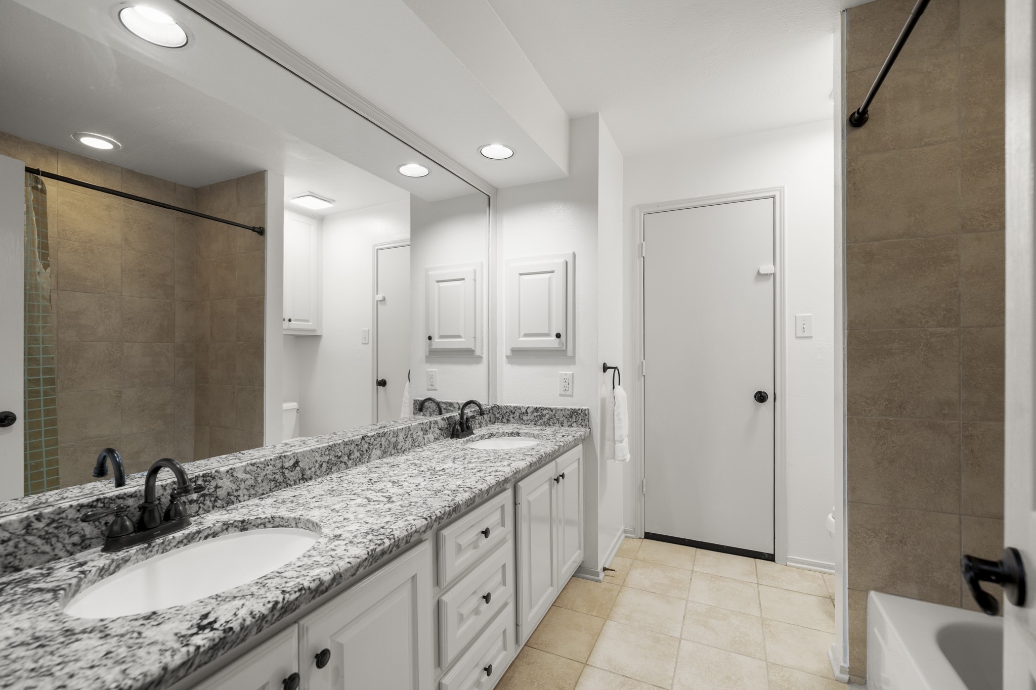102 Treescape Circle Spring, TX 77381 - Photo 21 of 40 This secondary bathroom features a dual-sink granite countertop, white cabinetry, and a combination shower/bathtub with neutral tile. The room is well-lit with recessed lighting, offering a clean and modern feel.