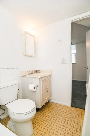 a bathroom with a granite countertop toilet a sink and a mirror