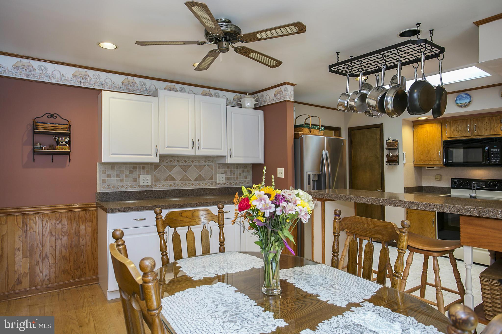 10009 German Road Ellicott City, MD 21042 - Photo 7 of 27 a kitchen with stainless steel appliances kitchen island granite countertop a table chairs in it and wooden floors