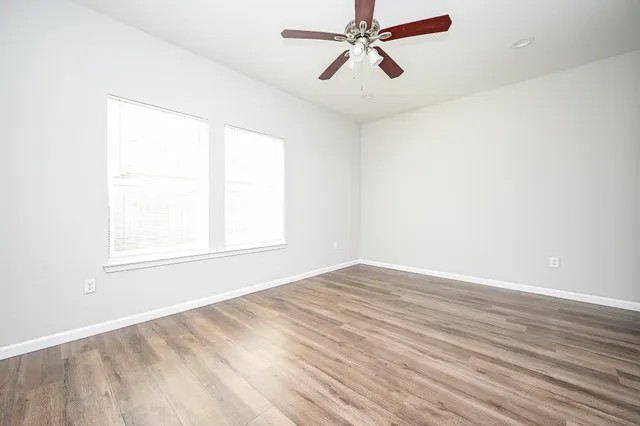 a view of empty room with wooden floor and fan