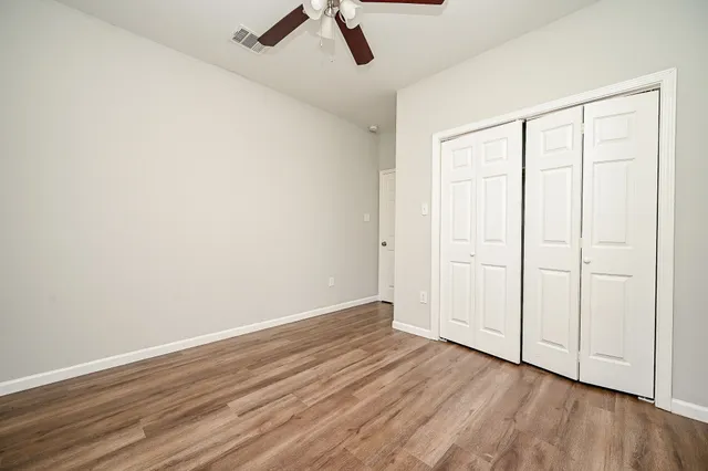 an empty room with wooden floor and windows