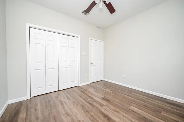 an empty room with a hardwood and ceiling fan