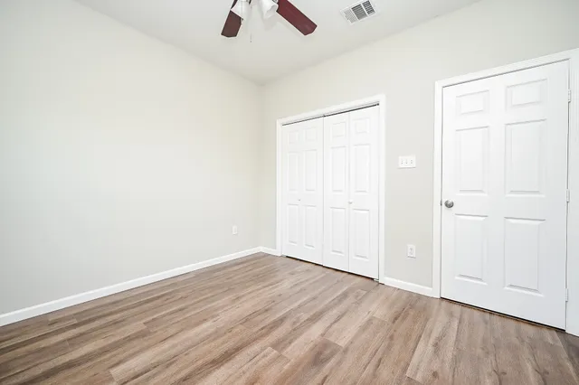 an empty room with a hardwood and ceiling fan
