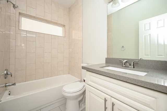 a bathroom with a granite countertop sink a toilet and bathtub