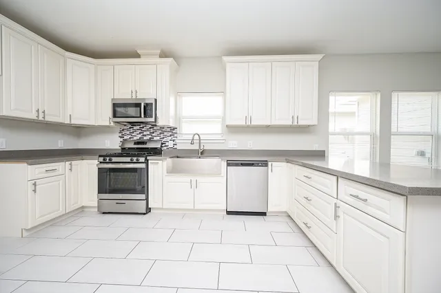 a kitchen with white cabinets appliances and a window