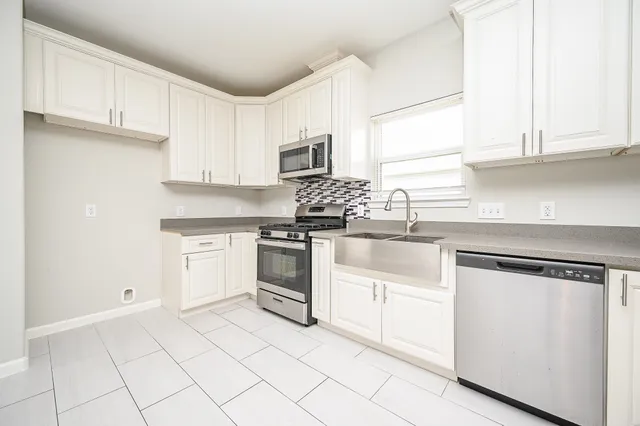 a kitchen with white cabinets and appliances