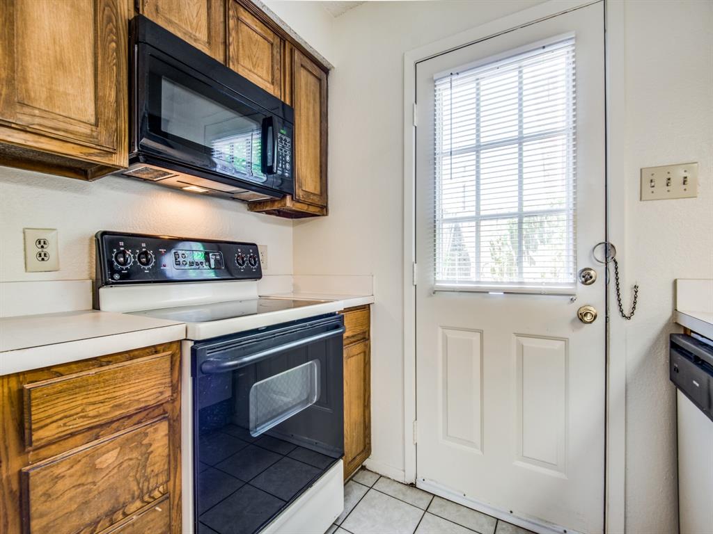 929 West Hickory Street, Unit A13 Denton, TX 76201 - Photo 5 of 12 a kitchen with granite countertop cabinets stainless steel appliances and a window