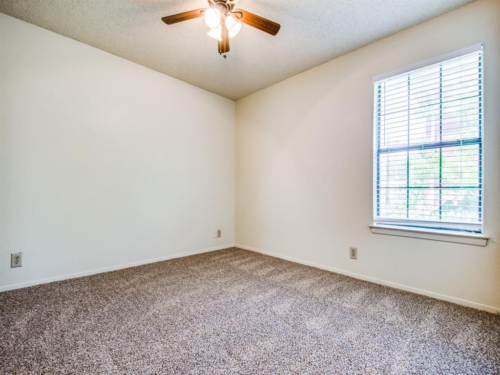 929 West Hickory Street, Unit A13 Denton, TX 76201 - Photo 8 of 12 an empty room with a chandelier fan and windows
