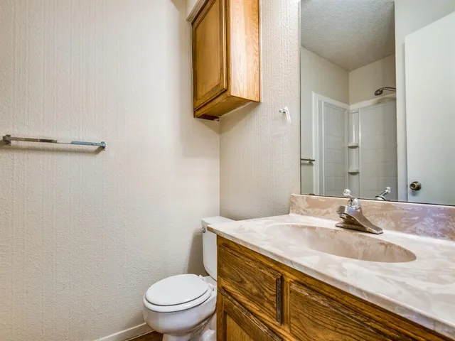 a bathroom with a granite countertop sink a toilet and a mirror
