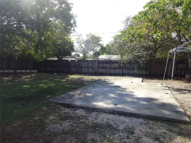 a view of a backyard with large trees and wooden fence