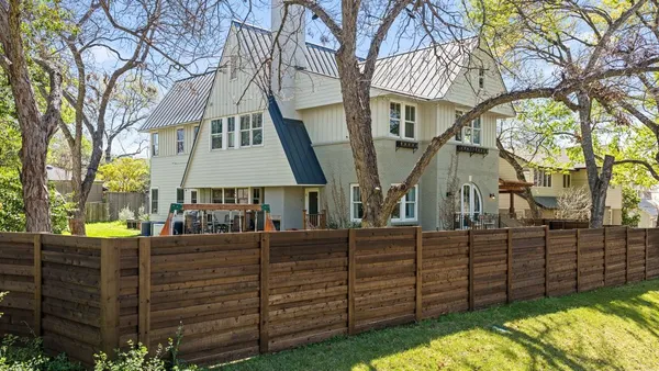 a view of a house with a wooden fence and a pathway
