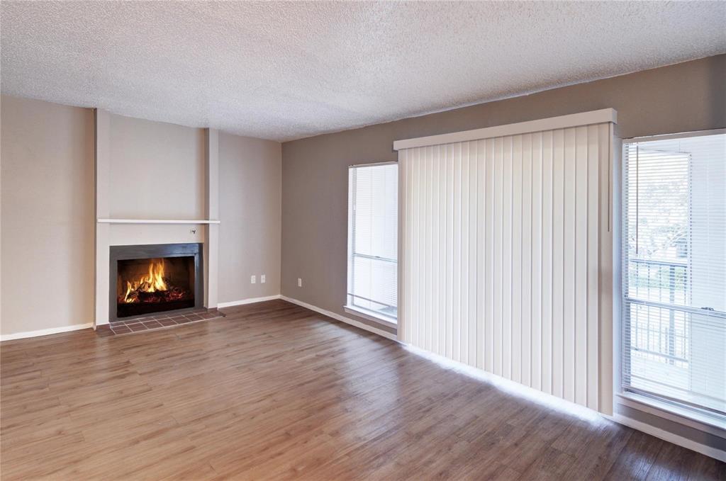 a view of an empty room with wooden floor fireplace and a window
