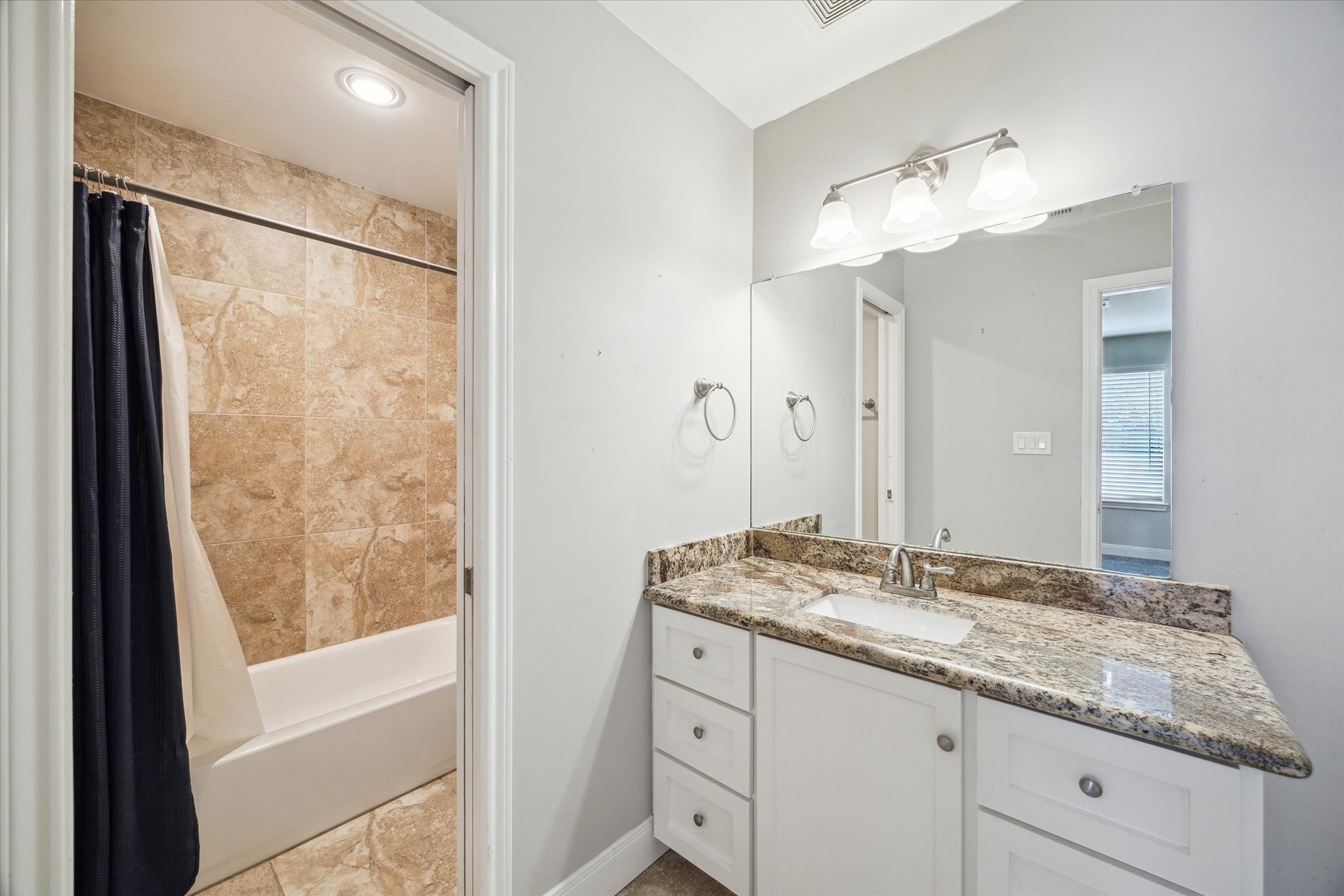 6047 Floyd Street Houston, TX 77007 - Photo 17 of 22 a bathroom with a granite countertop sink mirror and a shower