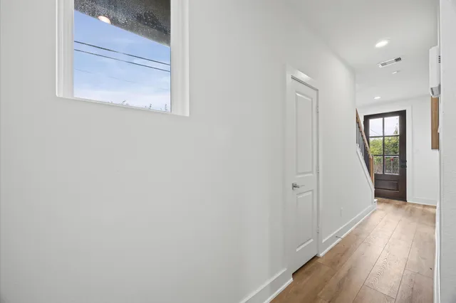 a view of a hallway with wooden floor and a window