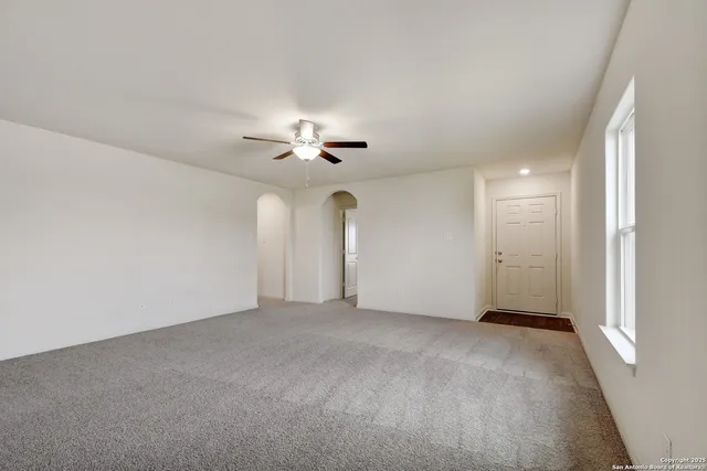 a view of an empty room with a chandelier fan