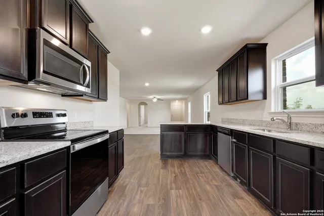 a kitchen with stainless steel appliances granite countertop wooden cabinets a stove top oven a sink and dishwasher