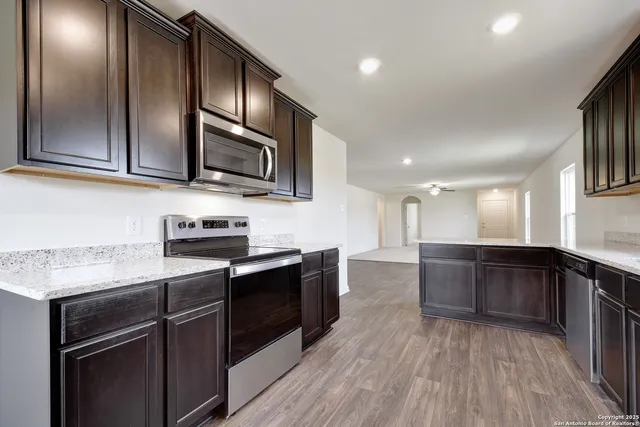 a kitchen with stainless steel appliances granite countertop wooden cabinets a stove top oven a sink and dishwasher