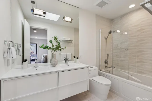 a bathroom with a double vanity sink toilet mirror and bathtub