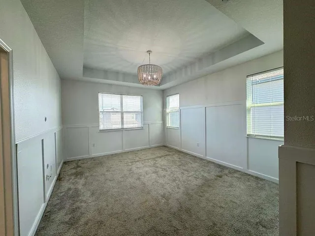 a view of an empty room and a chandelier fan