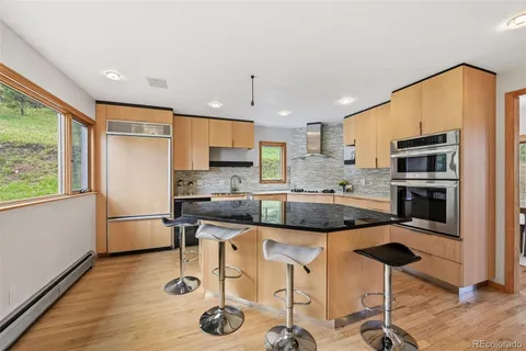 a kitchen with stainless steel appliances granite countertop a sink a stove a refrigerator cabinets and wooden floor