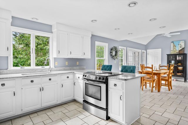 a kitchen with stainless steel appliances granite countertop white cabinets and window