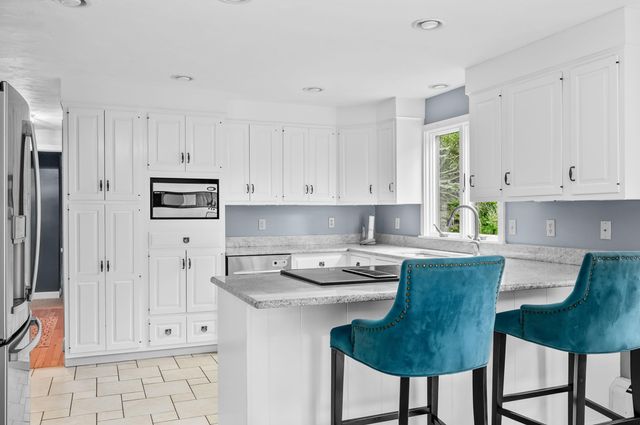 a kitchen with stainless steel appliances granite countertop a stove a refrigerator and white cabinets
