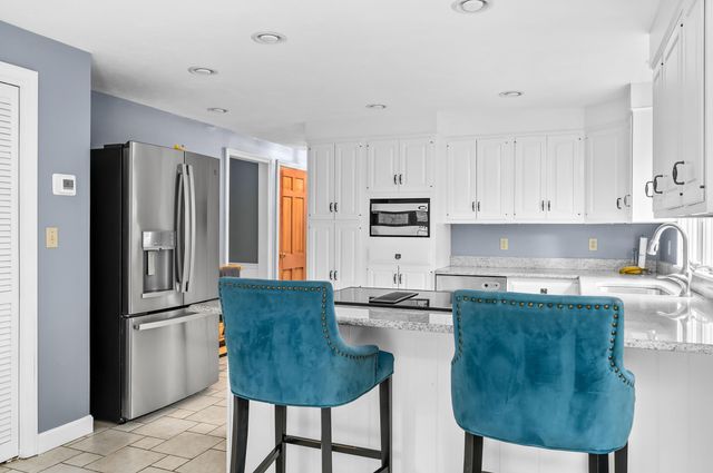 a kitchen with stainless steel appliances granite countertop a refrigerator a stove a sink and white cabinets