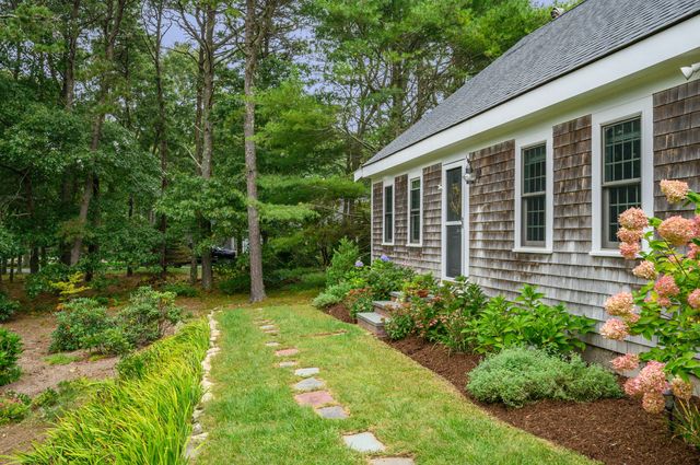 a yellow house with flower garden in front of it