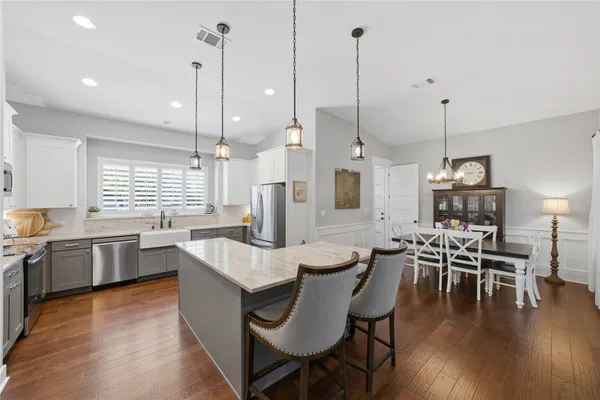 a dining room with furniture wooden floor kitchen view and a chandelier