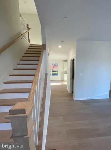 a view of an empty room with wooden floor and a bathroom