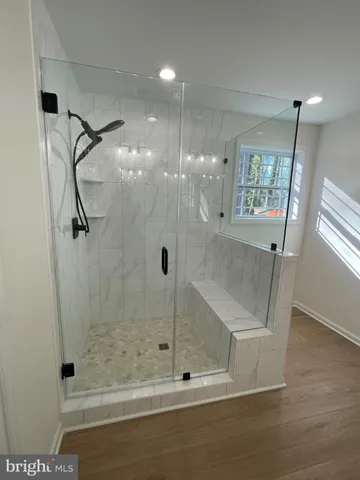 a view of an empty room with wooden floor and a bathroom