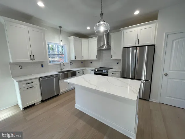a kitchen that has a lot of white cabinets and stainless steel appliances