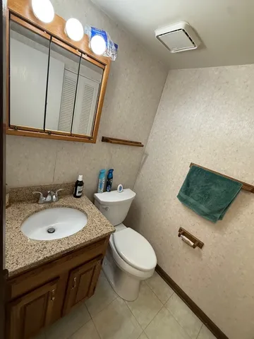 a bathroom with a granite countertop sink mirror and toilet