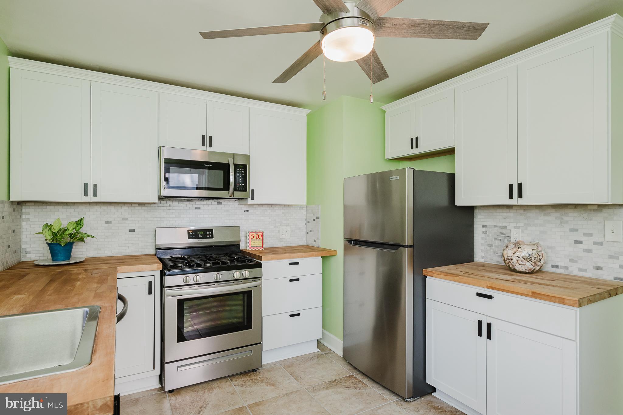 5501 Catalpha Road Baltimore, MD 21214 - Photo 12 of 40 a kitchen with a refrigerator a stove a microwave and cabinets