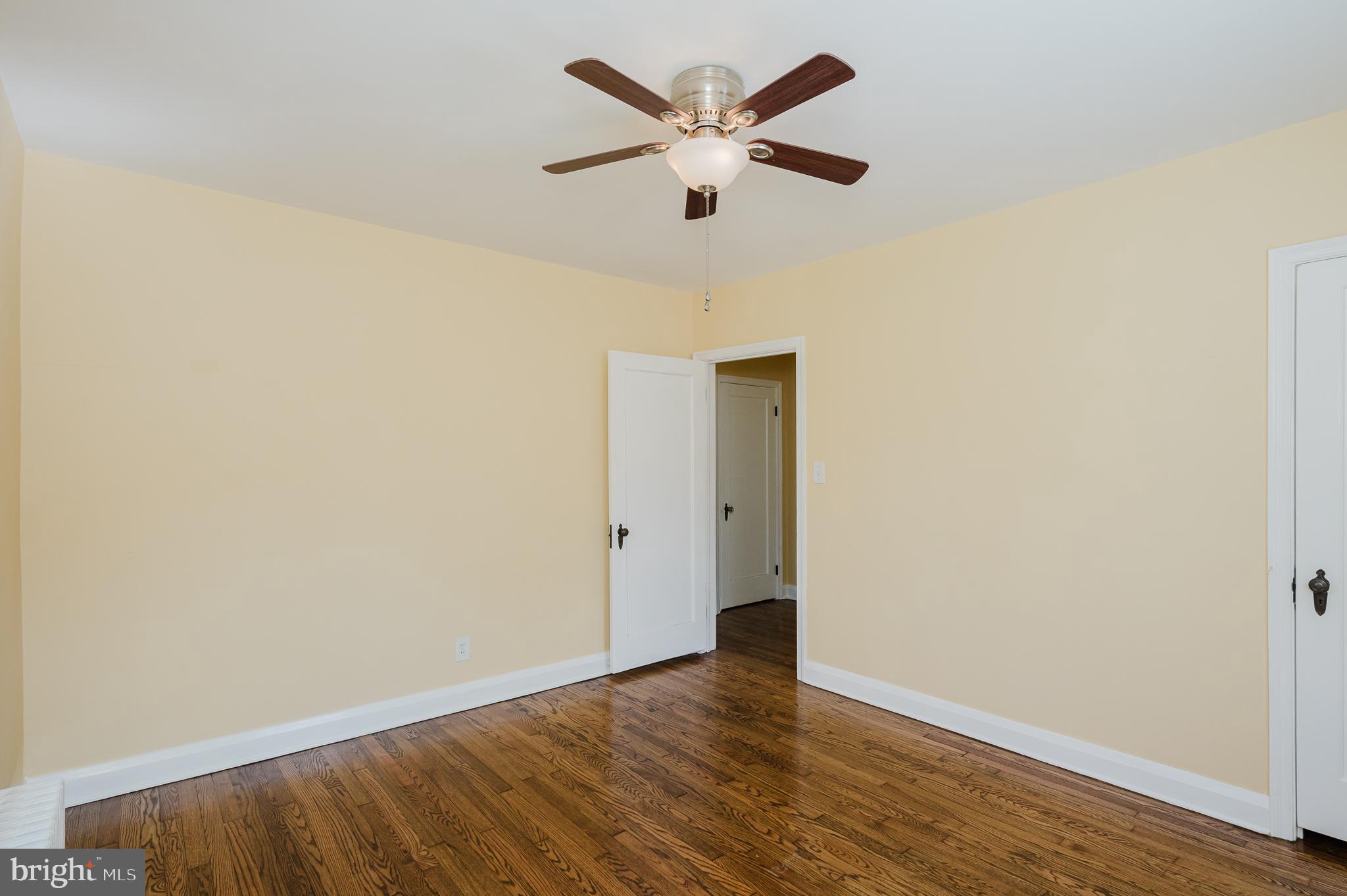 5501 Catalpha Road Baltimore, MD 21214 - Photo 17 of 40 an empty room with wooden floor and ceiling fan