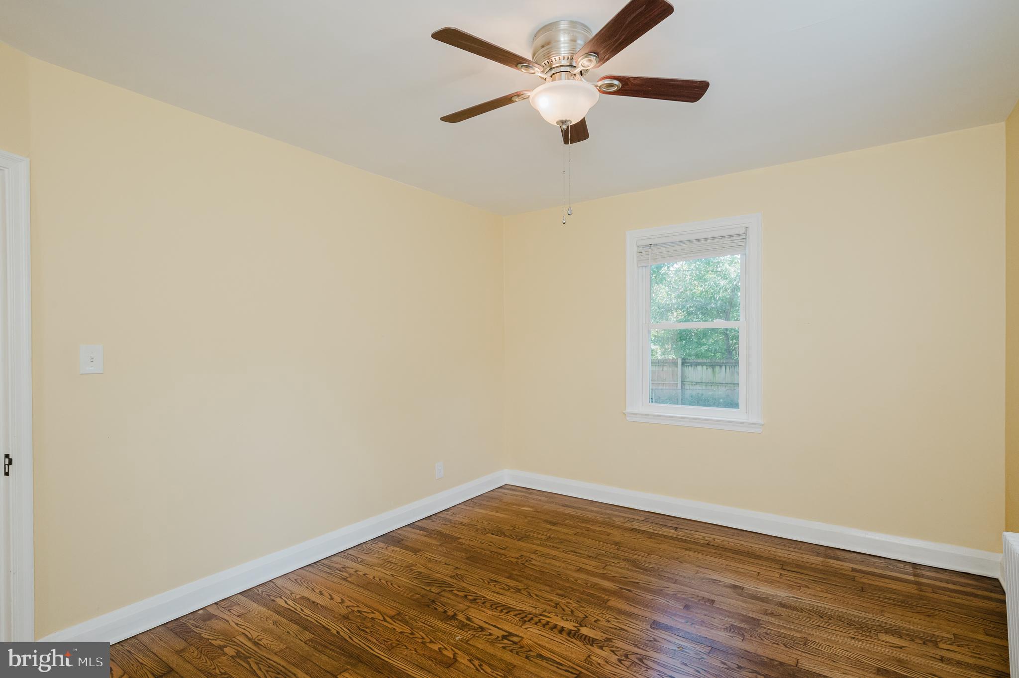 5501 Catalpha Road Baltimore, MD 21214 - Photo 23 of 40 an empty room with wooden floor fan and windows