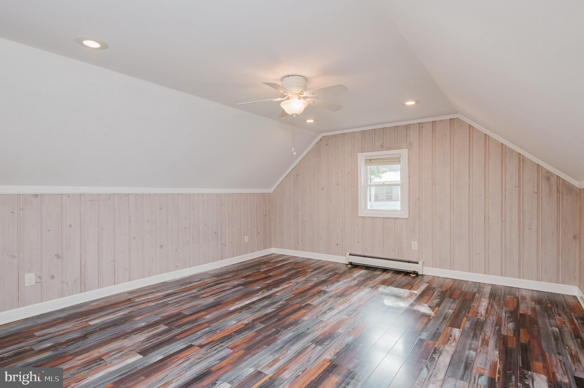5501 Catalpha Road Baltimore, MD 21214 - Photo 26 of 40 an empty room with wooden floor chandelier fan and windows