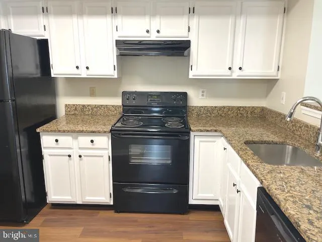 a kitchen with granite countertop a sink stove and refrigerator