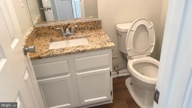 a bathroom with a granite countertop toilet and a sink