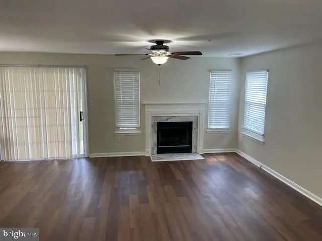 an empty room with wooden floor fireplace and windows