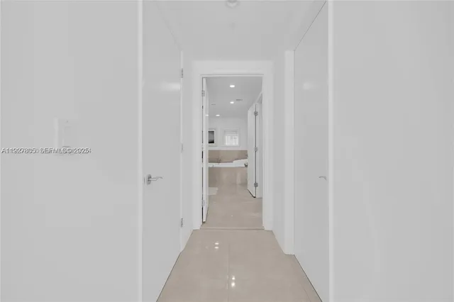 a view of a hallway with a livingroom and a bathroom with sink