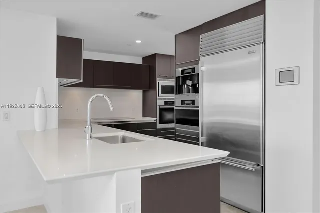 a kitchen with kitchen island a counter top space cabinets and stainless steel appliances