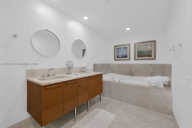 a bathroom with a tub double vanity sink and a mirror