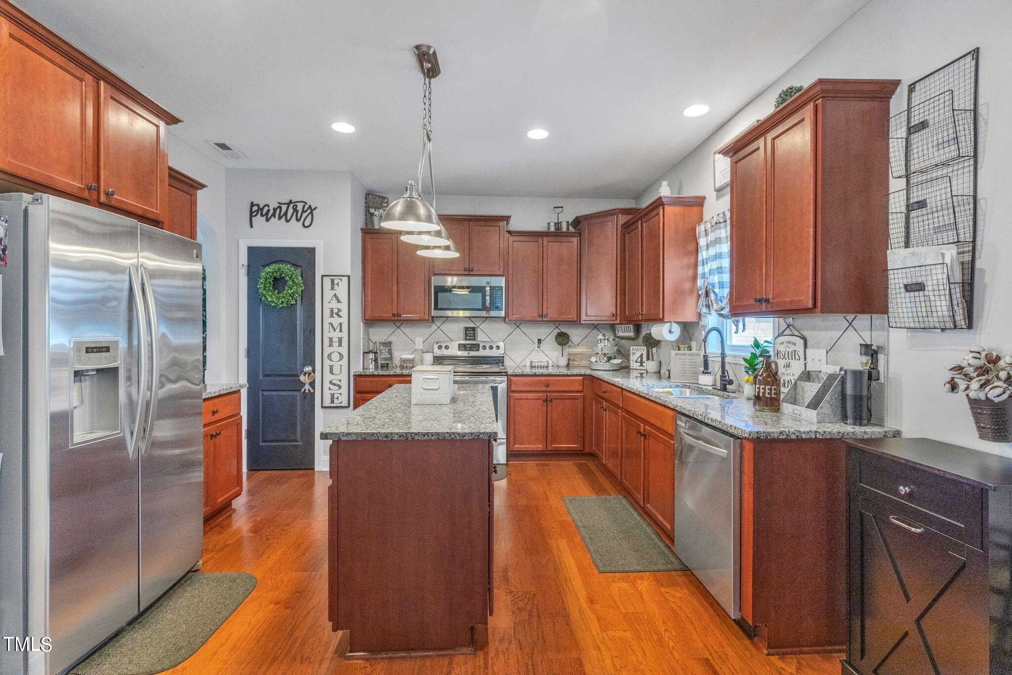 111 Oldstead Drive Raeford, NC 28376 - Photo 14 of 28 a kitchen with stainless steel appliances kitchen island granite countertop a stove a sink a refrigerator and cabinets