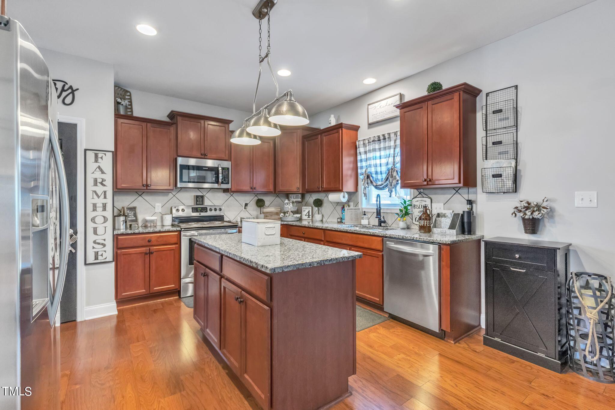 111 Oldstead Drive Raeford, NC 28376 - Photo 15 of 28 a kitchen with stainless steel appliances granite countertop a refrigerator a sink dishwasher a stove with wooden cabinets and floor