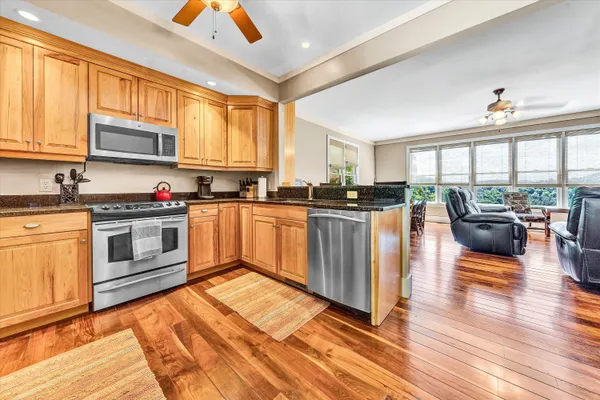 a kitchen with stainless steel appliances granite countertop a stove top oven a sink dishwasher a dining table and chairs with wooden floor