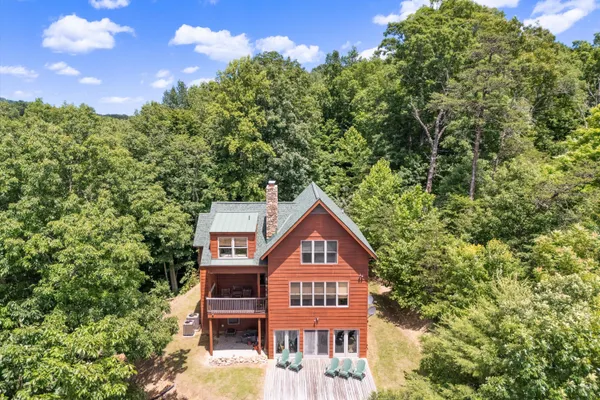 an aerial view of residential house with outdoor space and trees all around